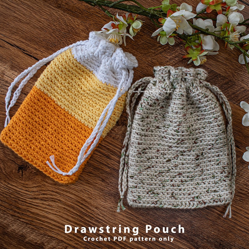 May include: Two crocheted drawstring pouches. One pouch is white, yellow, and orange. The other pouch is a speckled brown and white. The pouches are on a wooden surface. Drawstring Pouch Crochet PDF pattern only.