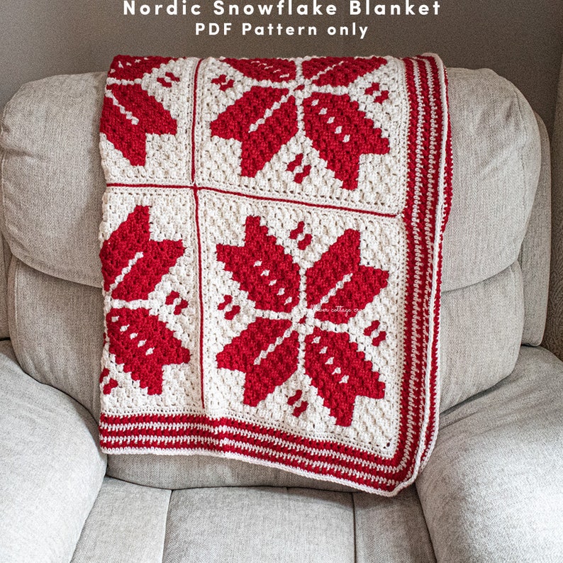 Puede incluir: Una manta de punto de ganchillo de copo de nieve blanca y roja con un borde. La manta est&aacute; doblada y drapeada sobre un sill&oacute;n gris claro. El texto "Nordic Snowflake Blanket PDF Pattern only" est&aacute; en la parte superior de la imagen.