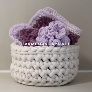 May include: A white crocheted basket filled with purple and white crocheted spa items. The basket is labeled "Farmhouse Spa Set" with the text "sunflower cottage crochet" below.