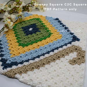 May include: A crocheted granny square in a C2C (corner-to-corner) pattern. The square features a central diamond design in shades of green, blue, and yellow, surrounded by a border of cream and brown. The text "Granny Square C2C Square PDF Pattern only" is visible.