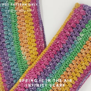 May include: A handmade, colorful infinity scarf with a crochet pattern. The scarf features a vibrant array of colors including pink, purple, green, yellow, and orange. Text on the scarf reads "Spring is in the air infinity scarf".