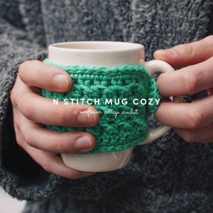 May include: A green crocheted mug cozy with the text "N Stitch Mug Cozy" and "© sunflower cottage crochet".