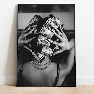 Puede incluir: Impresión en blanco y negro de una persona con billetes de dólar enrollados alrededor de la cabeza. La persona lleva un collar y una camiseta negra. La imagen está enmarcada en un borde negro.