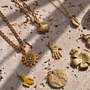 FeriaStudio | Vergoldete Kette mit Anhänger „dije“ Muschel, Sonne, Hand, Fossil, Blume, Erde, Banane, Goldkette