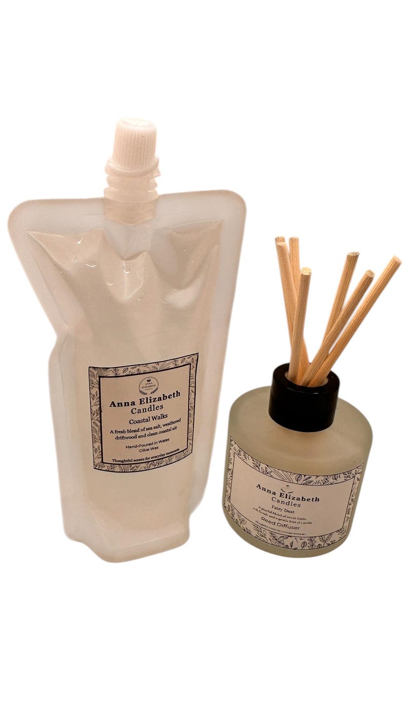 May include: A clear pouch and a glass bottle with reed diffuser sticks. Both feature labels with the text "Anna Elizabeth Candles" and "Coastal Walks" and "Fairy Dust". The pouch has a white cap.