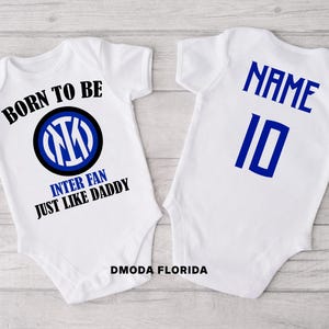 May include: Two white baby onesies. One has the text "BORN TO BE INTER FAN JUST LIKE DADDY" with a blue and black logo. The other has "NAME" and the number "10" in blue. The text "DMODA FLORIDA" is at the bottom.