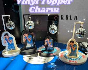 May include: Four vinyl record topper charms featuring a figure in a blue shirt with hands over their face, displayed on circular bases with L-shaped stands. Each stand holds a small, reflective, multi-faceted silver disco ball ornament.