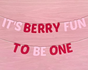 May include: Pink and red paper banner with the text "It's Berry Fun To Be One".