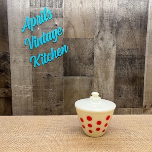 May include: A vintage cream-colored kitchen canister with a lid and red polka dots. The canister has a rounded shape and a small knob on top. The words "Aprils Vintage Kitchen" are in turquoise script in the background.