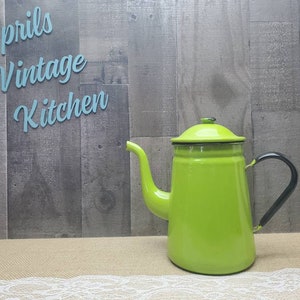 May include: A vintage lime green enamelware coffee pot with a black handle and spout. The pot has a matching lid and is set against a rustic wooden background. The text "Aprils Vintage Kitchen" is visible in the background.