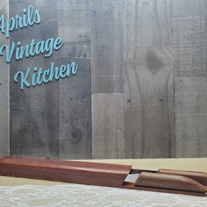 May include: A wooden shoe stretcher with a dark brown finish, resting on a cream-colored surface. The stretcher is inside a matching wooden box. The text "Aprils Vintage Kitchen" is in the background.