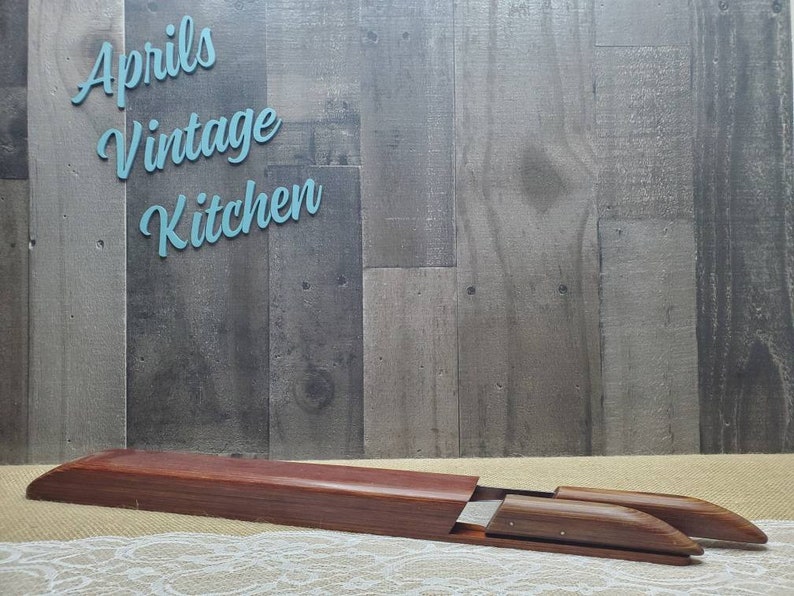 May include: A wooden shoe stretcher with a dark brown finish, resting on a cream-colored surface. The stretcher is inside a matching wooden box. The text "Aprils Vintage Kitchen" is in the background.