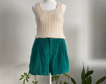 May include: A white knitted tank top with a cable knit pattern paired with green corduroy shorts. The outfit is displayed on a white mannequin.