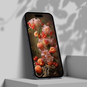 Op de afbeelding: Een zwarte smartphone toont een stilleven van perziken, roze bloemen en rode bessen. De telefoon staat op een wit oppervlak, met schaduwen op de achtergrond. De afbeelding op het scherm heeft een donkere, melancholische uitstraling.