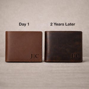 May include: Two brown leather bifold wallets displayed side by side. The left wallet is labelled Day 1 and is a lighter tan colour. The right wallet is labelled 2 Years Later and is a darker, weathered brown. Both feature the embossed initials J|C.