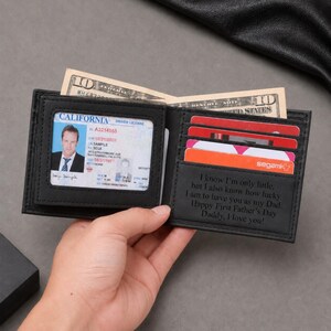 K&ouml;nnte beinhalten: Ein schwarzes Leder-Bifold-Portemonnaie mit einem transparenten Ausweisfach, das einen kalifornischen F&uuml;hrerschein enth&auml;lt, mehreren Kartenf&auml;chern und einer Innengravur mit dem Text, I know I'm only little, but I also know how lucky I am to have you as my Dad. Happy First Father's Day Daddy, I love you!