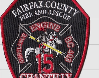 May include: A black embroidered patch with a red border featuring the text FAIRFAX COUNTY FIRE AND RESCUE, ENGINE 15, CHANTILLY, SINCE 1947, AMBULANCE, and BC 403. The center depicts a knight on a horse holding a yellow lance with red accents.