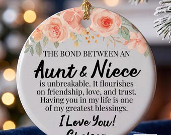 Könnte beinhalten: Ein runder, weißer Keramikschmuck mit einem Blumenmuster aus rosa Rosen an der Oberseite. Der Text lautet: THE BOND BETWEEN AN Aunt & Niece is unbreakable. It flourishes on friendship, love, and trust. Having you in my life is one of my greatest blessings. I Love You! Chelsea. Er hängt an einer goldenen Schnur.