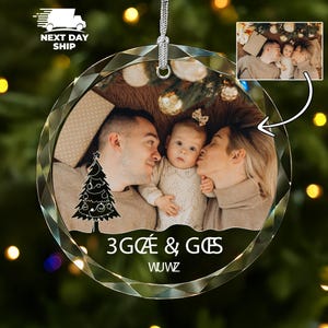 May include: A circular, faceted glass Christmas ornament featuring a printed photograph of a family of three. The ornament includes a white graphic of a Christmas tree, the text 3G&OElig; & G&OElig;S, and the word WUWZ in white lettering.