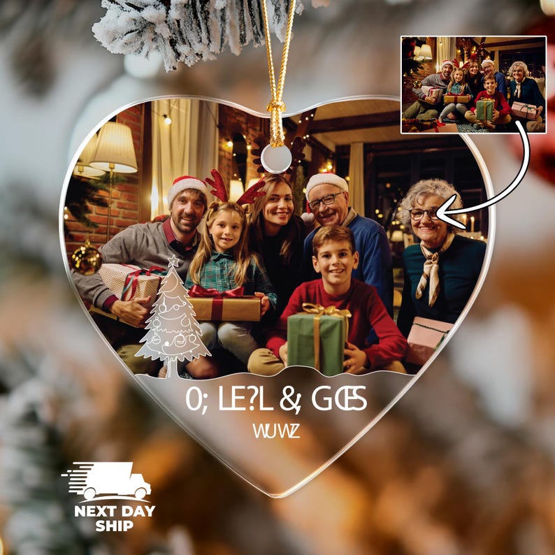 May include: A heart-shaped clear acrylic ornament featuring a printed photograph of a family exchanging gifts in a living room. The ornament includes a white line-art Christmas tree graphic, the text O; LE?L & GES WUWZ, and a gold hanging cord.