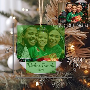May include: A round ceramic Christmas ornament measuring 3 inches by 3 inches, featuring a custom family photo, a line-art Christmas tree graphic, and the text Walter Family 2024. The ornament hangs from a jute twine loop against a blurred tree background.