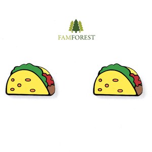 May include: Two yellow and green cartoon taco earrings. The tacos have a red sauce and brown filling.