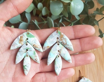 May include: Dangle earrings featuring three layered leaf-shaped segments in a marbled pattern of mint green, white, and sage green with gold foil accents. The segments are connected by small gold-toned metal jump rings and attached to gold-toned posts.