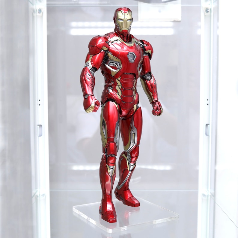 Puede incluir: Una figura de acci&oacute;n de Iron Man roja y dorada con acabado met&aacute;lico. La figura est&aacute; de pie sobre una base de acr&iacute;lico transparente.