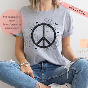 Könnte beinhalten: Graues T-Shirt mit einem schwarzen Peace-Zeichen, das von Blumen und Sternen umgeben ist. Der Text "Mit Bügeleisen, oder Transferpresse anzubringen" befindet sich auf dem Shirt.