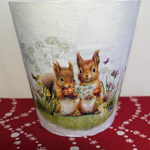 May include: White ceramic planter with a textured surface. The planter features a colourful illustration of two squirrels in a garden setting.