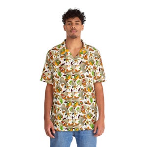 May include: Short-sleeved button-down shirt with a white background and a repeating pattern of cartoon characters wearing sombreros and holding maracas. The shirt has a V-neck collar and is worn with blue jeans.