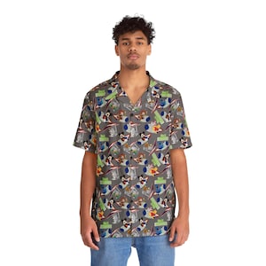 May include: Grey short-sleeved shirt with a cartoon space-themed print. The shirt has a camp collar and is worn with blue jeans. The print includes the word "SPACE" in green.