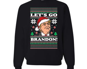 May include: Black sweatshirt with a festive design. The graphic features a portrait of a man wearing a Santa hat, with the text "LET'S GO BRANDON!" in white. The design includes snowflakes, Christmas trees, and red and green accents.