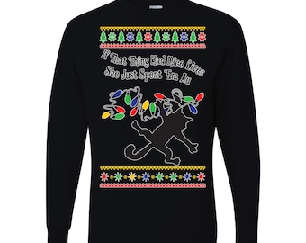 May include: Black long-sleeve shirt with a festive design. The shirt features a silhouette of a cat tangled in Christmas lights, with the text "If That Thing Had Nice Lives She Just Spent 'Em Au" above the cat and between the decorative borders.