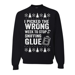 May include: Black sweatshirt with white text that reads "I PICKED THE WRONG WEEK TO STOP SNIFFING GLUE." The design includes snowflakes and Christmas trees. A glue bottle graphic is also present.