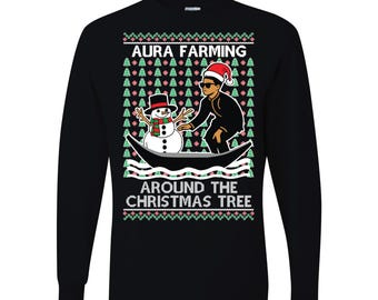 May include: Black long-sleeve shirt with a festive design. The shirt features the text "AURA FARMING" and "AROUND THE CHRISTMAS TREE". The graphic shows a person in a Santa hat and sunglasses with a snowman in a boat, surrounded by Christmas trees.