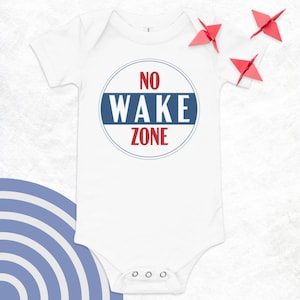 May include: White baby onesie with a blue and red circle that says "NO WAKE ZONE" in white letters.