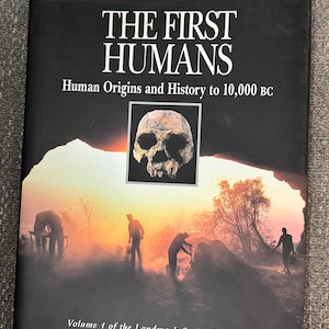 May include: A book titled "THE FIRST HUMANS" with the subtitle "Human Origins and History to 10,000 BC." The cover features a skull image and a landscape with silhouettes of people. It is Volume 1 of the Landmark Series from the American Museum of Natural History.
