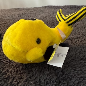 May include: Yellow and black plush whale toy with a black and white striped tail. The toy has a tag that reads "With Our Compliments The 30th Series of Wildlife Animals 1993".
