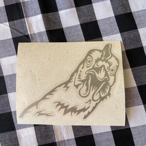 May include: A gray vinyl sticker of a chicken's head with a detailed design. The chicken is looking to the right and has a surprised expression.