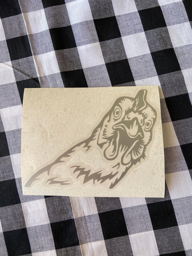 May include: A gray vinyl sticker of a chicken's head with a detailed design. The chicken is looking to the right and has a surprised expression.