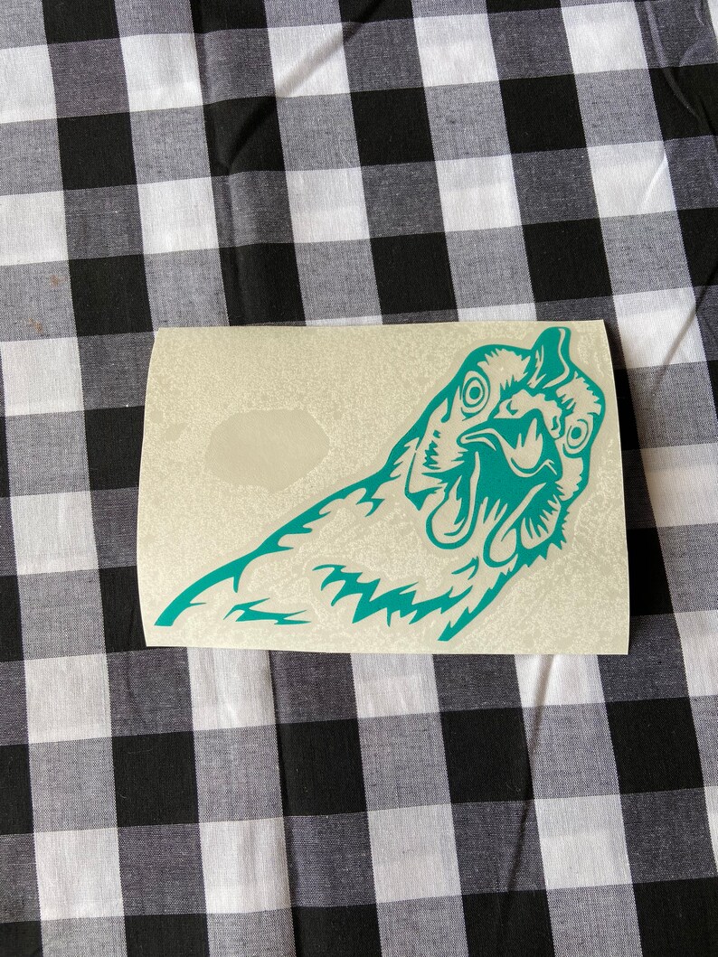 May include: A teal blue vinyl sticker of a chicken's head with its beak open. The sticker is on a white background.