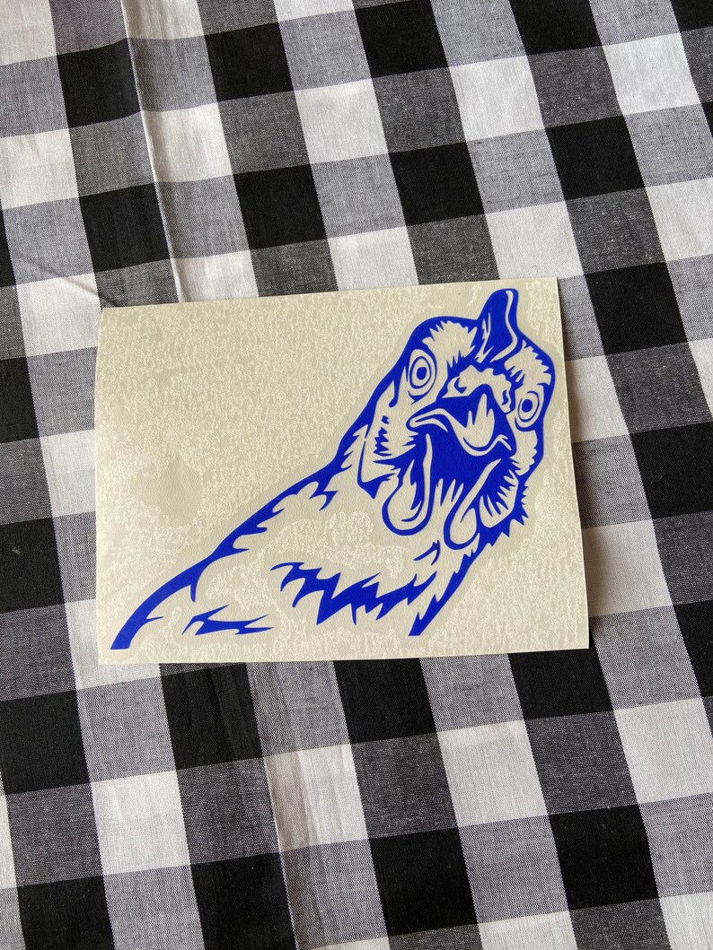 May include: A blue vinyl decal of a chicken's head with its beak open, looking directly at the viewer. The decal is on a white background.