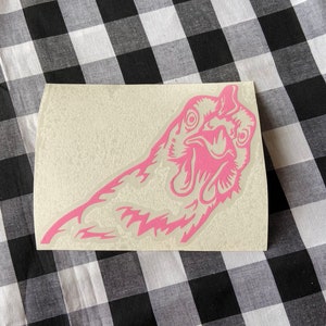 May include: Pink vinyl sticker of a chicken's head with a surprised expression.
