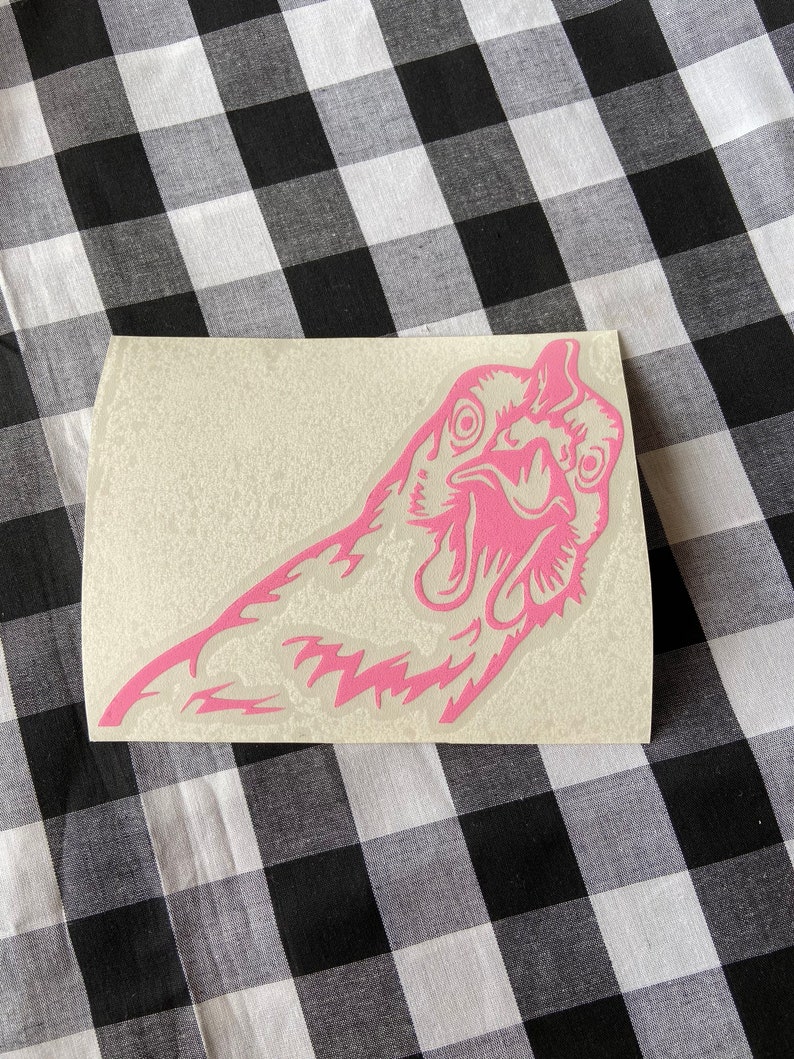 May include: Pink vinyl sticker of a chicken's head with a surprised expression.