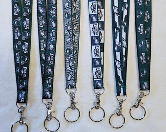 May include: Six different Philadelphia Eagles lanyard keychains with a green and white colour scheme. Each lanyard features a different design with the Eagles logo and the word "Eagles".
