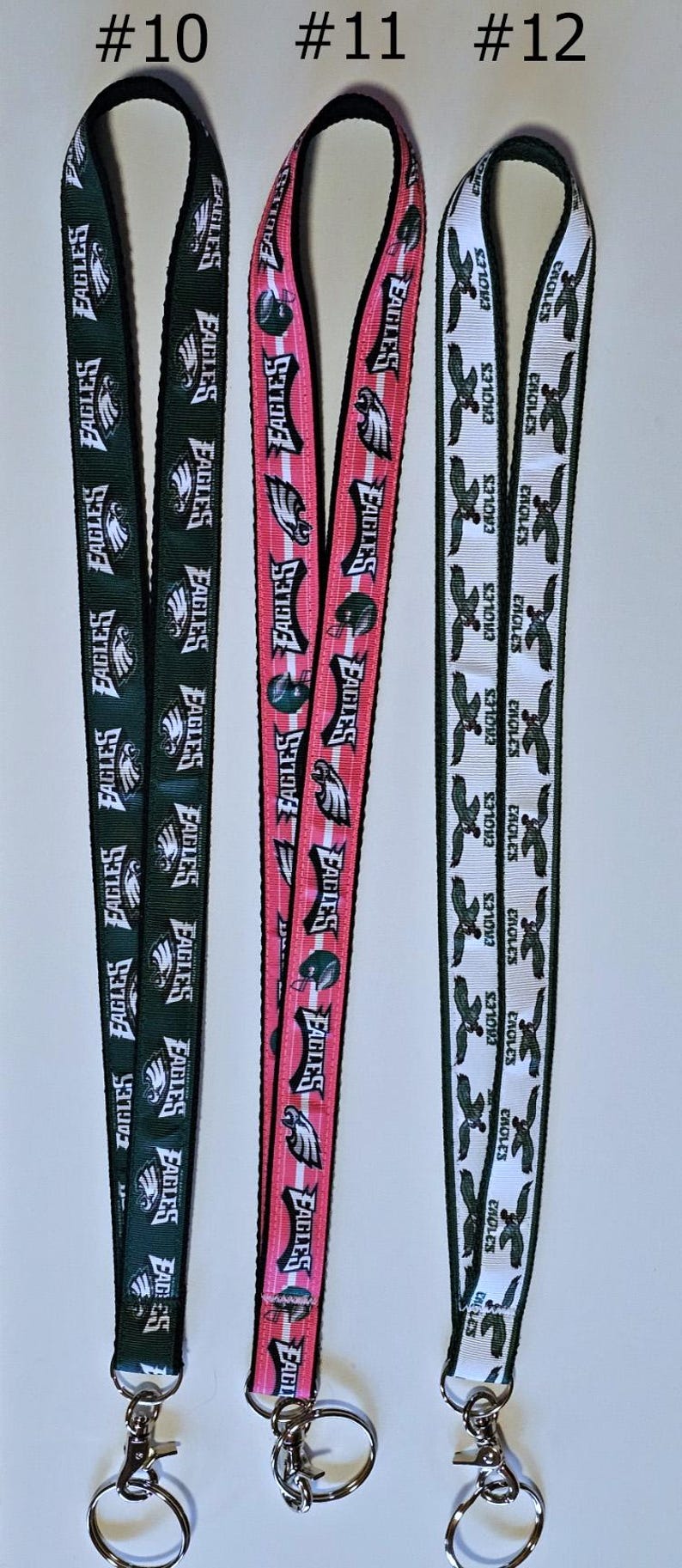 Puede incluir: Tres llaveros diferentes con cord&oacute;n y el logotipo de los Philadelphia Eagles. El primer cord&oacute;n es verde con letras blancas, el segundo es rosa con letras blancas y el tercero es blanco con letras verdes. Cada cord&oacute;n tiene un llavero plateado.