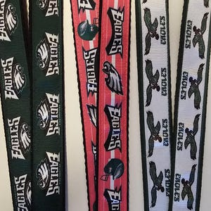 Puede incluir: Cuatro llaveros diferentes con el logotipo y el nombre del equipo de los Philadelphia Eagles. Los llaveros son verdes, rojos, blancos y negros.