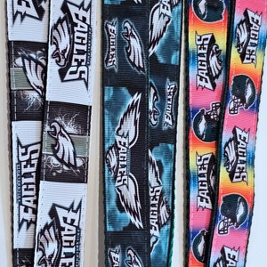 Puede incluir: Tres dise&ntilde;os diferentes de cinta de tela con el logotipo de los Philadelphia Eagles. La primera cinta es blanca con detalles negros y presenta un gran logotipo de &aacute;guila. La segunda cinta es negra con detalles azules y presenta un gran logotipo de &aacute;guila. La tercera cinta es de colores arco&iacute;ris con detalles negros y presenta un gran logotipo de &aacute;guila.