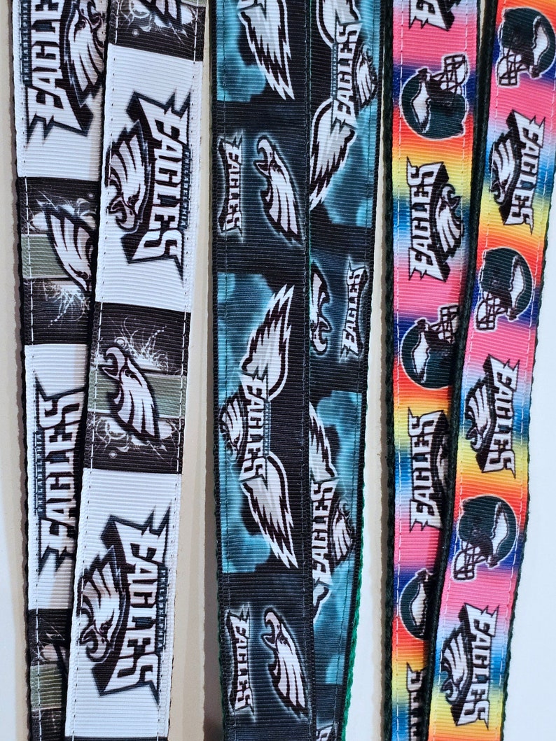 Puede incluir: Tres dise&ntilde;os diferentes de cinta de tela con el logotipo de los Philadelphia Eagles. La primera cinta es blanca con detalles negros y presenta un gran logotipo de &aacute;guila. La segunda cinta es negra con detalles azules y presenta un gran logotipo de &aacute;guila. La tercera cinta es de colores arco&iacute;ris con detalles negros y presenta un gran logotipo de &aacute;guila.